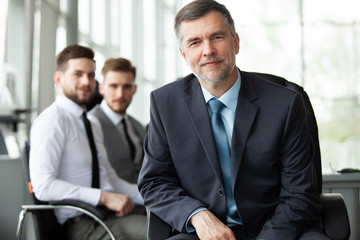 Mature smiling business manager in front of his business team