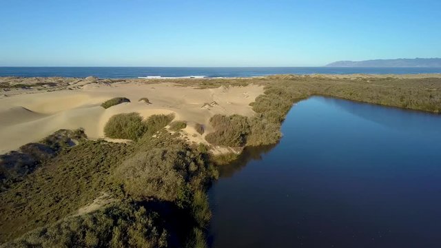 Beautiful aerial drone shot of tranquil sandy dunes next to a lake in Oso Flaco, located on the Central Coast of California, Santa Barbara County