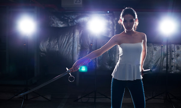 Beautiful Asian Woman demonstrates practice martial art Samurai blade knife technique threat weapon attack, Concept Girl Self Defense thief. Studio lighting rim back light dark low exposure silhouette