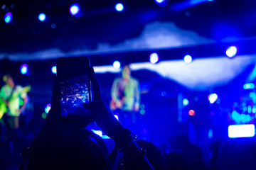 Fototapeta na wymiar Woman taking a photo with phone at music event