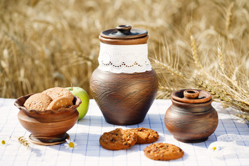 Obraz na płótnie Canvas Cookies apple and milk crokery on the wheat field rustic table