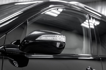 Fototapeta premium Close-up of the mirror of the car body black sedan on the street parking in the snow.