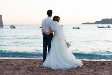 Fototapeta na wymiar newlyweds stand on the beach and look at the sea