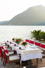 table for a wedding dinner decorated with red flowers and greenery