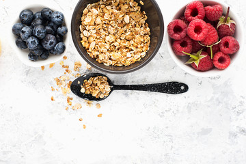 Berries fruit granola oatmeal raspberries, blueberries, bananas, honey, honeycombs, apples, kiwi on a light background. Top view. Copy space.