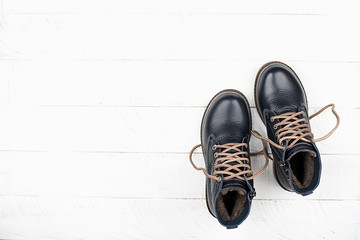 Dark blue leather schoolboy boy shoes on wooden white background. Top view. Copy space.