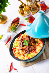 Tajin with couscous, vegetables and meat on white background