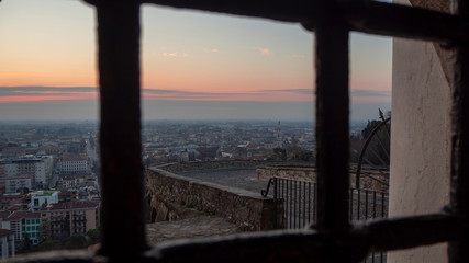 Bergamo, the old town, one of the beautiful city in Italy. Sunrise from behind the metal gate of Porta San Giacomo. Panorama on the lower city