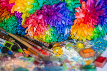 multi-colored chrysanthemums on the palette with paints and brushes of the artist