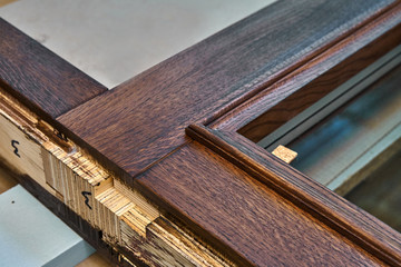 Wood door manufacturing process. Glazed door frame, painted in dark color. Furniture manufacture.