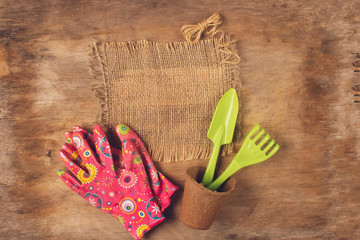 Garden tools, pots for plants and gloves on aged wooden background. Copy space.
