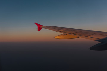 Wing of a plane flying in a dusky sky