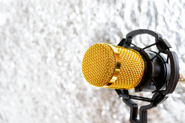 Beautiful golden microphone on a light blurred background, close up, bokeh.