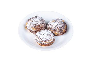 three choux cakes with sugar powder on top on a white plate isolated on white background
