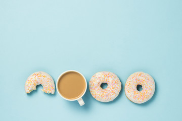 White Cup, coffee or tea with milk and fresh tasty donuts on a blue background. Bakery concept, fresh pastries, delicious breakfast, fast food. Flat lay, top view.