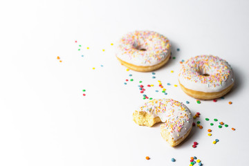 Fresh tasty donuts and sweet multicolored decorative candy on a white background. Bakery concept, fresh pastries, delicious breakfast.