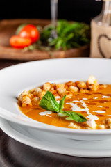 The concept of Italian cuisine. Pumpkin cream soup with orange flavor, chicken pieces, bread croutons and cream. A string of red wine on the table. Serving dishes in the restaurant