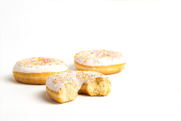 Fresh tasty donuts and sweet multicolored decorative candy on a white background. Bakery concept, fresh pastries, delicious breakfast.