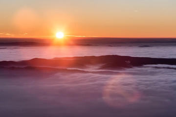 Fototapeta na wymiar Beautiful sunset over a valley filled by fog with mountains and hills