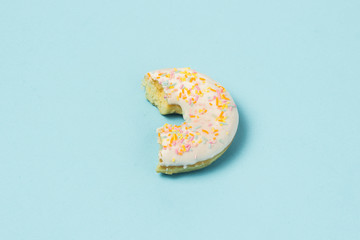 Bitten Fresh tasty sweet donut on a blue background. Fast food concept, bakery, breakfast. Minimalism.