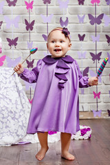 Little happy toddler girl celebrating first birthday. Cute baby girl with candy