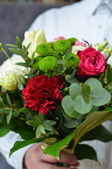 A bouquet of colorful flowers held by a man