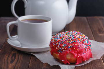 fresh tasty donut, cup of tea and teapot on wooden background