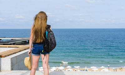 Naklejka premium girl tourist looks over the beach and sea
