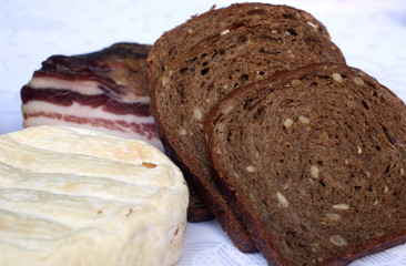 Rustic still life of bread, cheese and bacon in a wicker basket