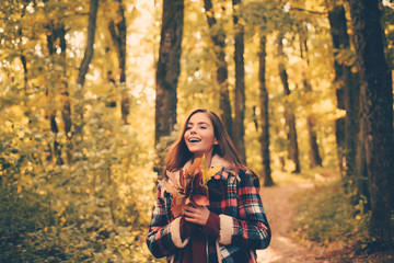 Fototapeta na wymiar Cheerful beautiful girl in red sweater outdoors on beautiful fall day. Autumnal mood. Romantic Young Woman on Natural Background Outdoors. Portrait of beautiful caucasian woman walking outdoors.