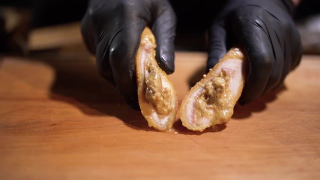 Hands in black rubber gloves crush the juicy patty in the dough close up