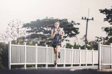 young woman runner running on running road in city park