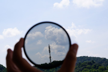A man hand holding a circular polariser filter pointing at the sky