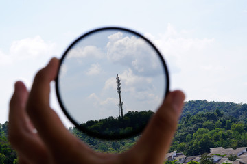 A man hand holding a circular polariser filter pointing at the sky