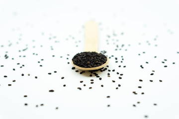 Black sesame on wooden spoon isolated on white background.