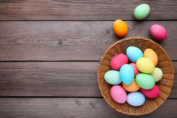 Obraz premium Colorful easter eggs in basket on grey wooden background