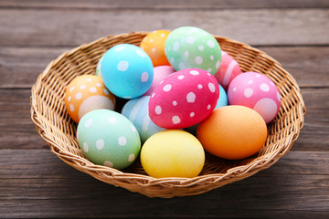 Colorful easter eggs in basket on grey wooden background