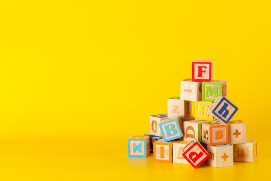 Colorful wooden blocks with letters on a yellow color background