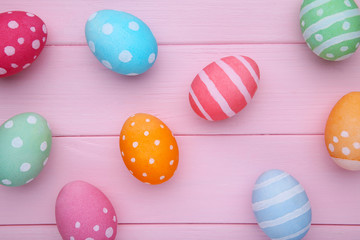 Fototapeta na wymiar Colorful easter eggs on a pink wooden background