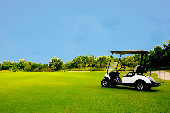 Golf cart car in fairway of golf course with fresh green grass field and cloud blue sky and tree