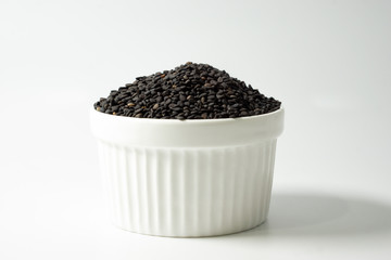 Fototapeta na wymiar Black sesame seed in white ramekin isolated on white background.