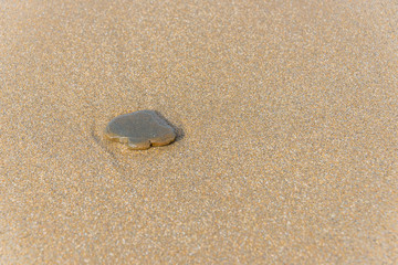 Fototapeta na wymiar Spade Shaped Stone on a Sandy Beach with Surf