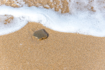 Spade Shaped Stone on a Sandy Beach with Surf