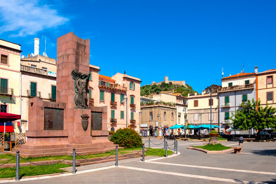 Sardinia, Italy - Memorial of the Fallen - Monumento ai Caduti - at the Corso Vittorio Emanuele in the Bosa city center with Malaspina Castle, known as Castle of Serravalle in background