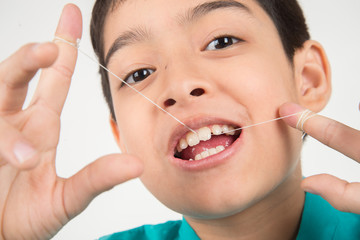 Little boy using dental floss to clean tooth