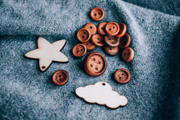 wooden buttons that are randomly placed on a gray background.next wooden toy silhouette lamb, star, month, mountain, cactus
