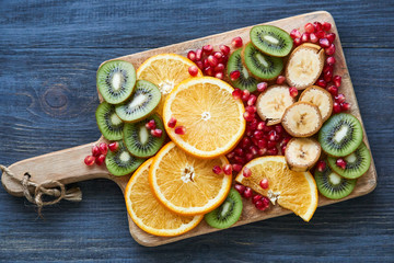 Different slices of fresh fruit on a wooden cutting board
