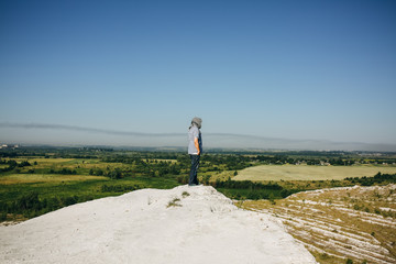 Man is standing on the white hill and looking at the landscape view with the green field. White...