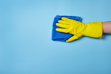Hand in protective glove cleaning blue wall. Cleaning concept.