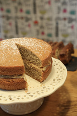 Traditional homemade sponge cake with delicious cream and icing on top for party on white plate.